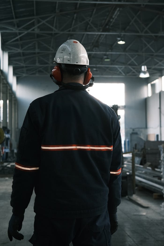 A worker in safety gear stands in a modern factory, emphasizing safety and industry innovation.