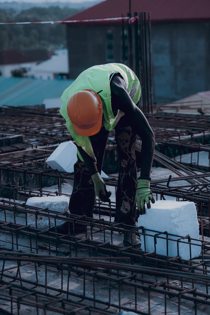 Construction worker with safety gear placing concrete block. Urban building site during the day.